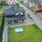 Aerial view of private house with green backyard and small swimming pool on grass lawn