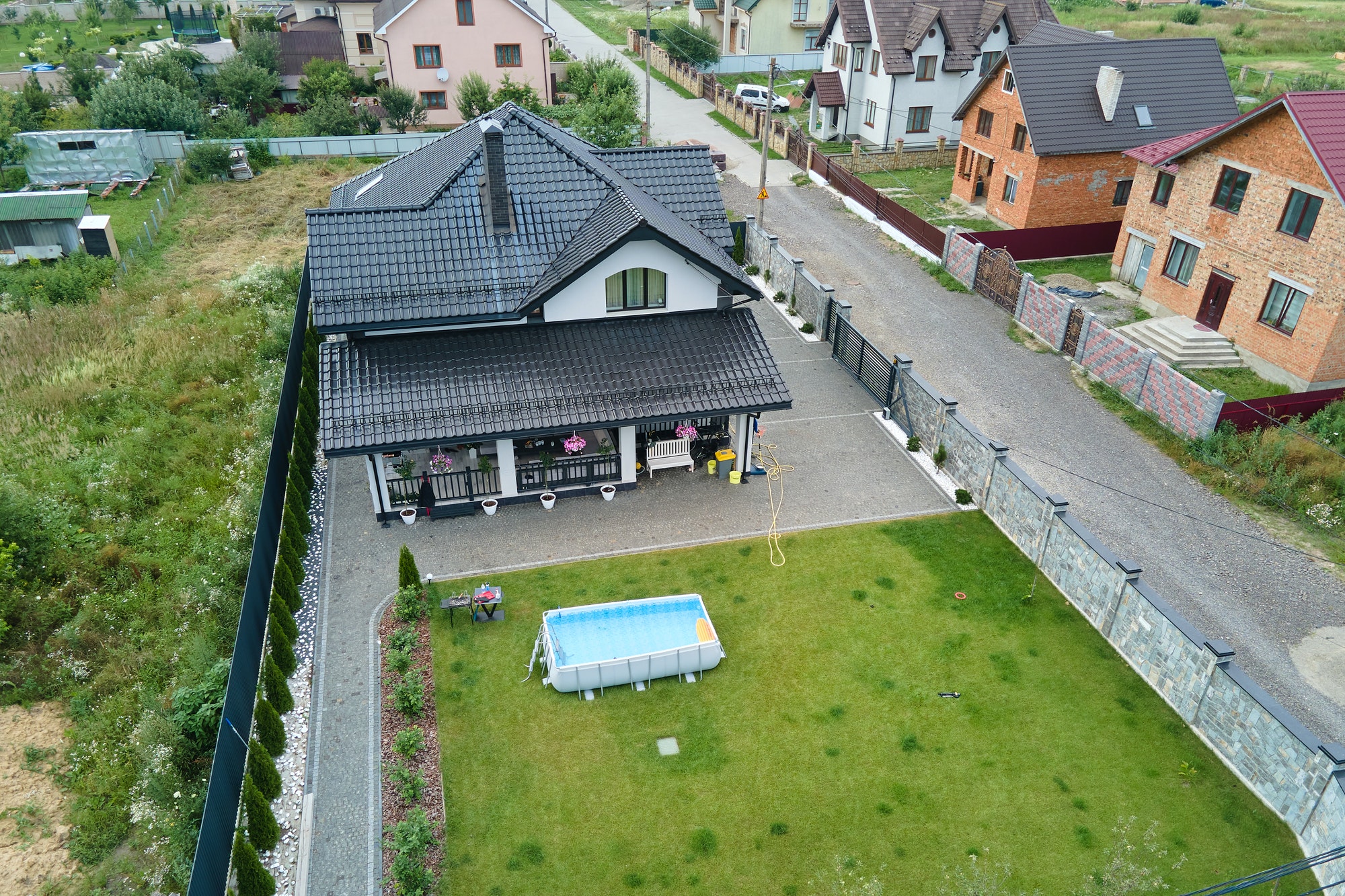 Aerial view of private house with green backyard and small swimming pool on grass lawn