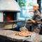Chef puts freshly baked hot pizza from a spatula in a box. Catering kitchen work.