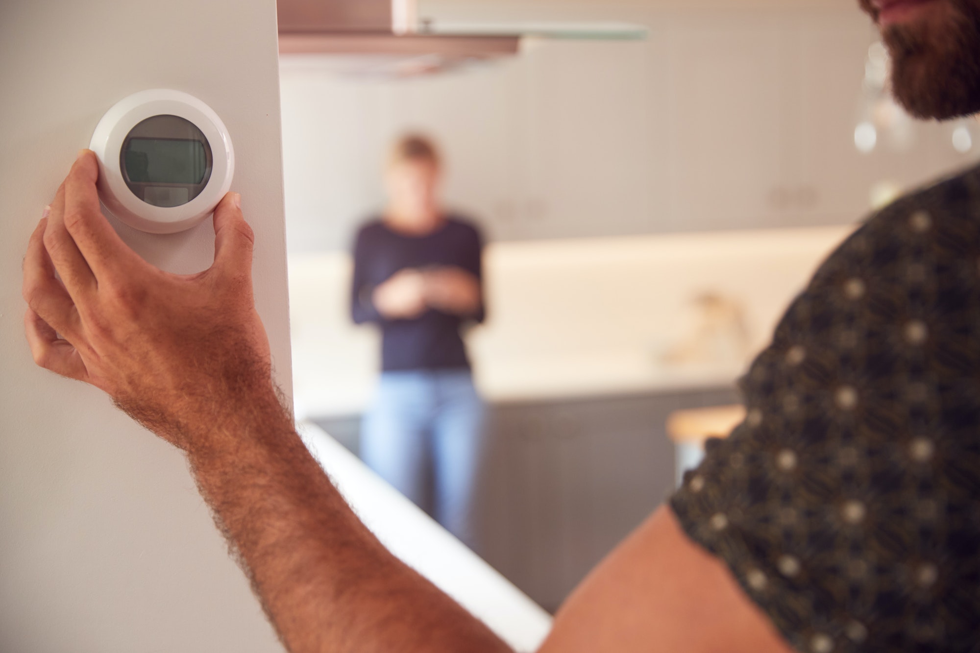 Close Up Of Man Adjusting Wall Mounted Digital Central Heating Thermostat Control At Home