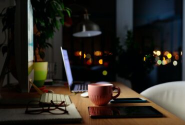 Comfortable workspace for distance job at home - mug of tea, laptop, lamp, tablet, mobile, plant