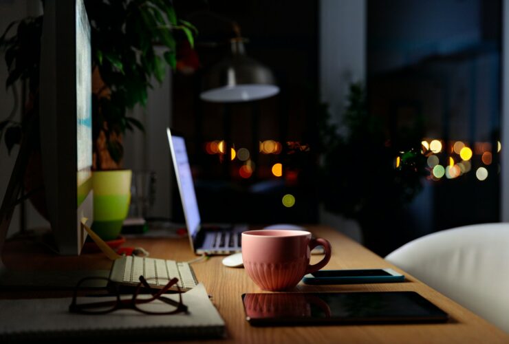 Comfortable workspace for distance job at home - mug of tea, laptop, lamp, tablet, mobile, plant