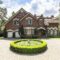 Front view of a driveway with a round garden and big, english st