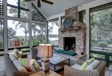 Luxurious three season screen porch with fireplace, looking out onto waterfront property.
