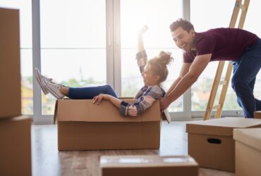 Playful couple having fun with boxes during move house