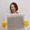 Woman holding dirty and dusty ventilation grille, disgusted