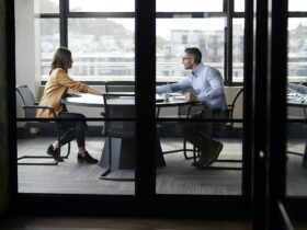 A businessman and young woman meeting for a job interview, full length, seen through glass wall