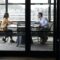 A businessman and young woman meeting for a job interview, full length, seen through glass wall