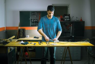 A man performs some electrical repairs in the garage of his house.