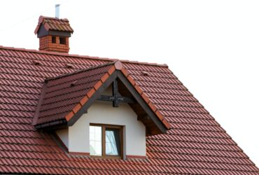 Close up of new orange roof with chimney and small modern window. Concept of modern roof with