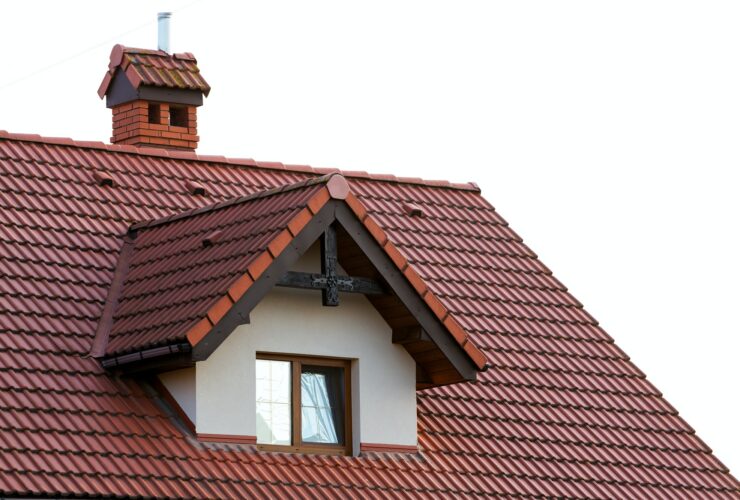 Close up of new orange roof with chimney and small modern window. Concept of modern roof with