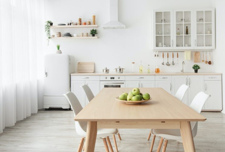 Contemporary minimalist interior of kitchen and dining room. White furniture with utensils and