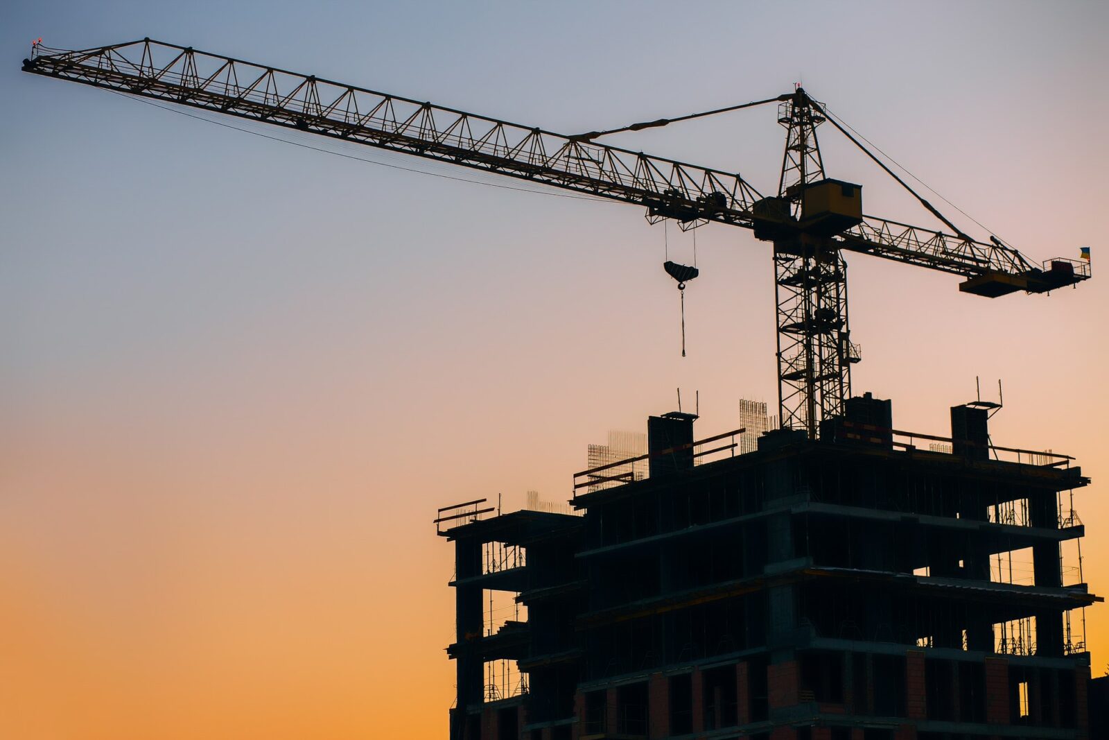Crane and building construction site on background of sunset sky