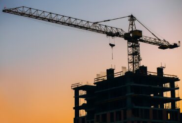 Crane and building construction site on background of sunset sky