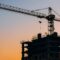 Crane and building construction site on background of sunset sky