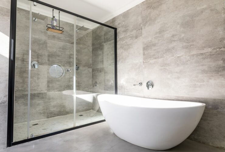 Empty bathtub by modern shower in bathroom at home