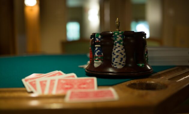 Poker chips and deck of cards sitting on edge of poker table.