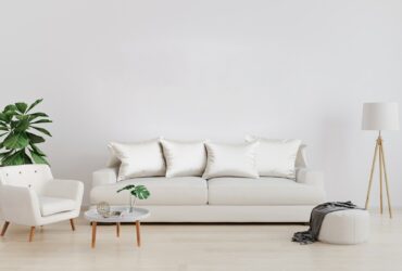 Stylish interior of bright living room with white sofa and armchair, floor lamp, plant