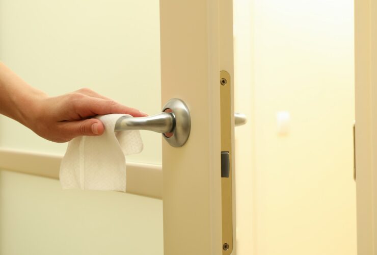 Woman hand using antibacterial wet wipe for disinfecting door handle