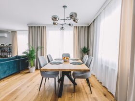 Dining room with wooden table and floor in modern apartment.