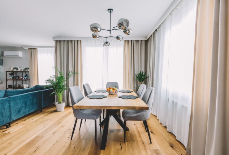 Dining room with wooden table and floor in modern apartment.