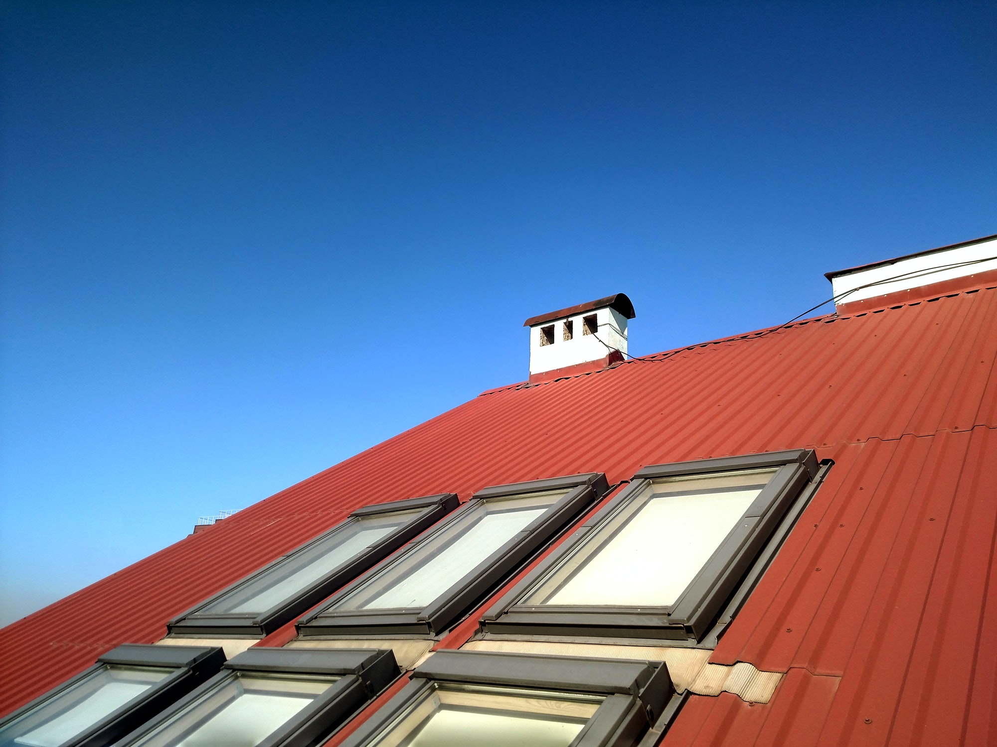 Red tiled house roof with attic windows. Roofing construction, window installation, modern