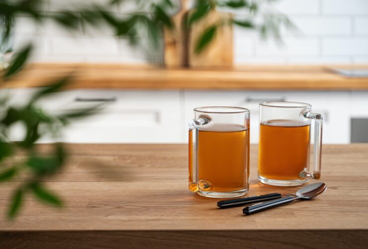 Two cups of tea and brunch close up on wooden countertop against the background of a white kitchen