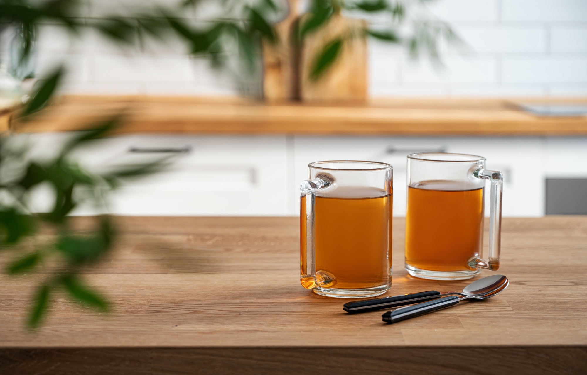 Two cups of tea and brunch close up on wooden countertop against the background of a white kitchen