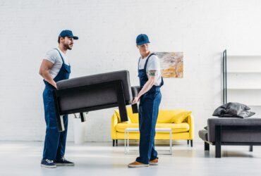two movers in uniform transporting furniture in apartment