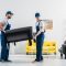 two movers in uniform transporting furniture in apartment