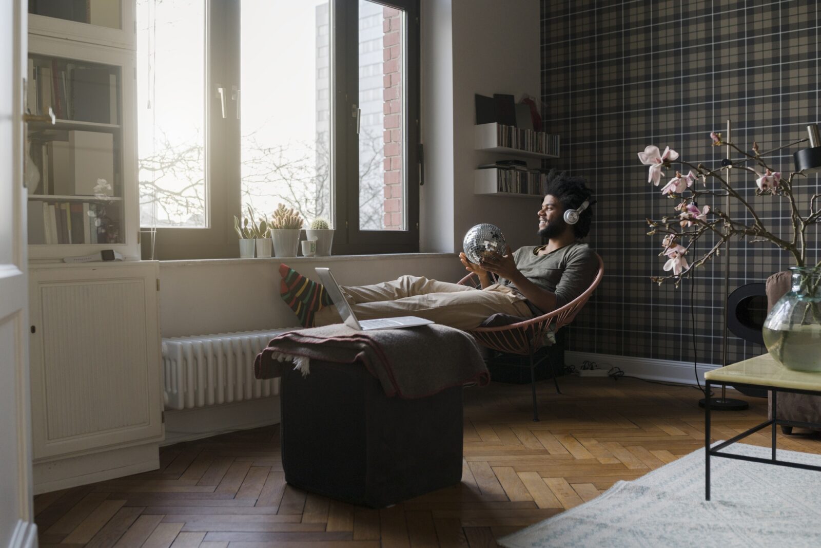 Man sitting in living room in armchair holding mirror ball listening to music