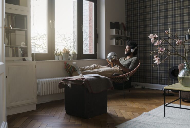 Man sitting in living room in armchair holding mirror ball listening to music