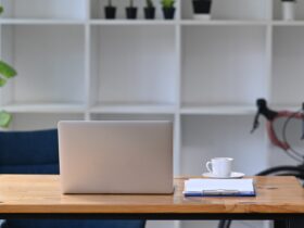 Mock up computer laptop on wooden table with bicycle in home office.