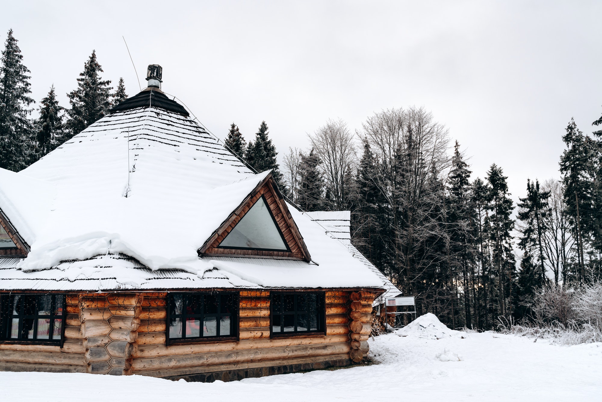 Old wooden house in the snow. Traditional typical house or villa in the countryside in winter.