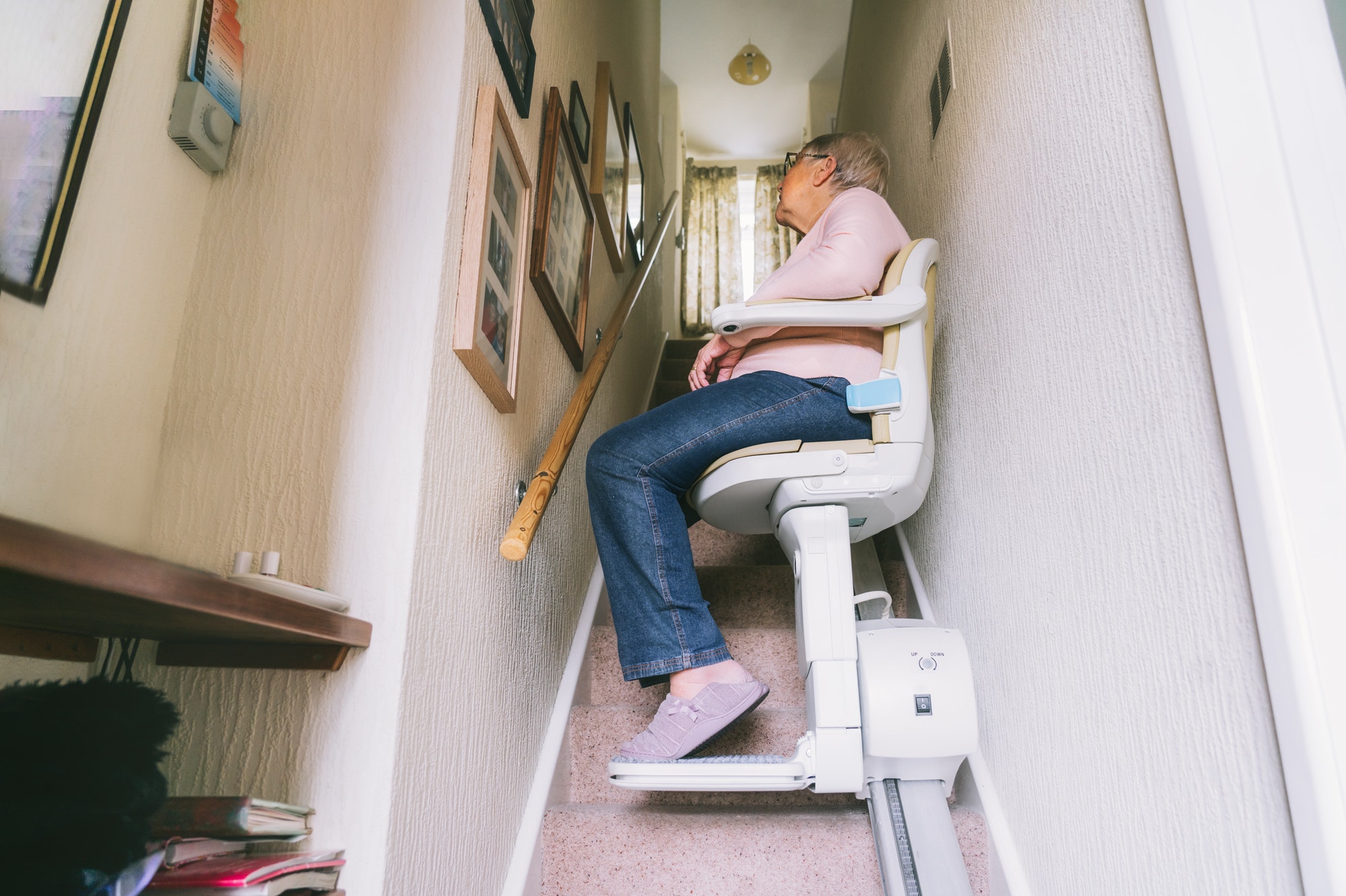 Senior woman using automatic stairlift on a staircase at her home. Medical Stairlift for disabled