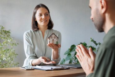 woman realtor or mortgage consultant holds a miniature model of a house and the keys to an apartment