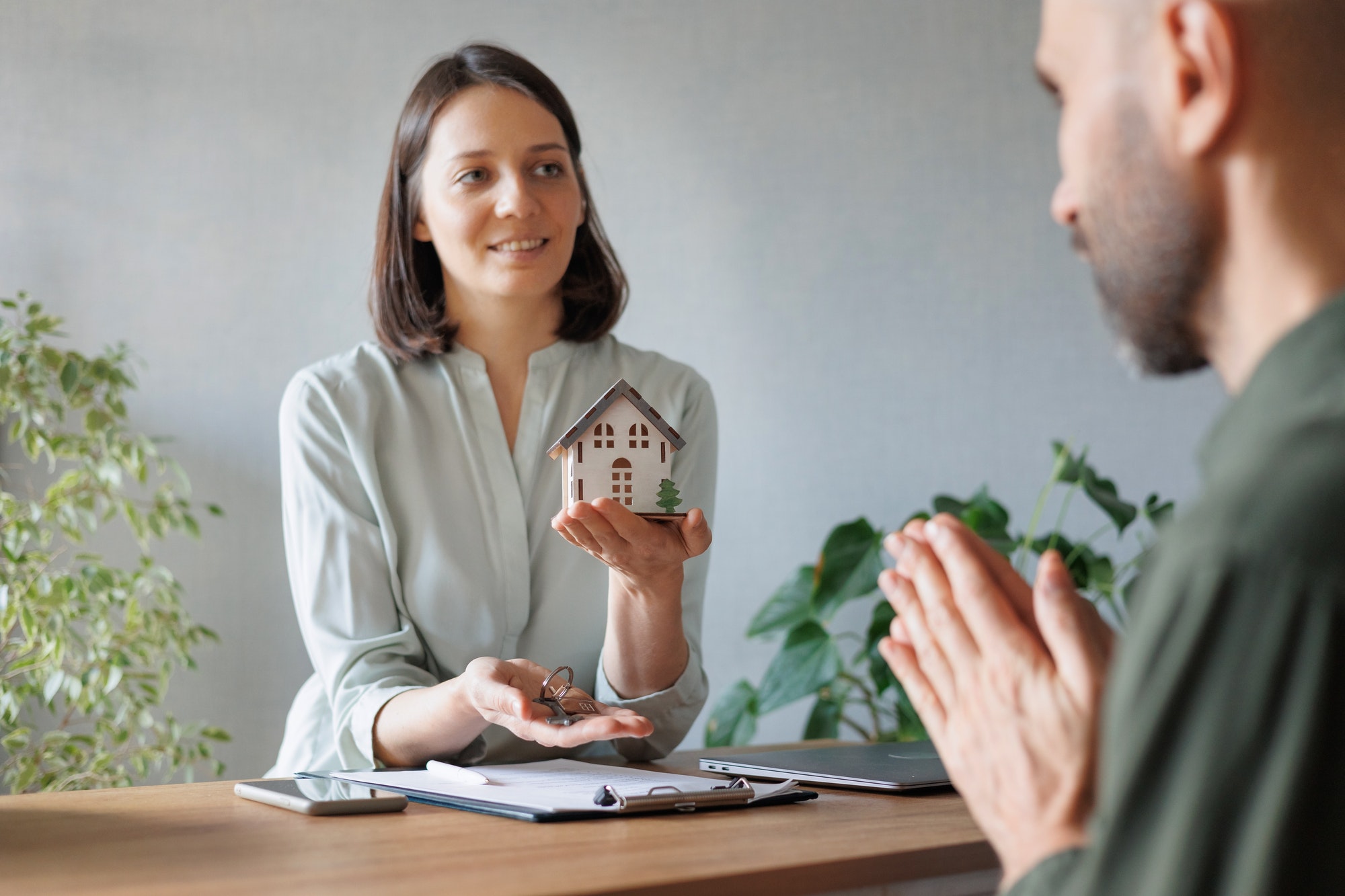 woman realtor or mortgage consultant holds a miniature model of a house and the keys to an apartment