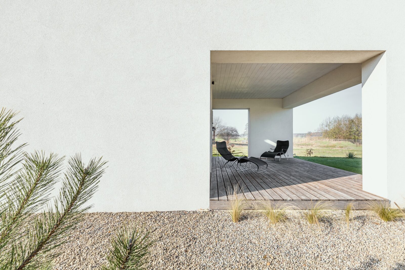 Black trendy armchairs on wooden patio of modern house