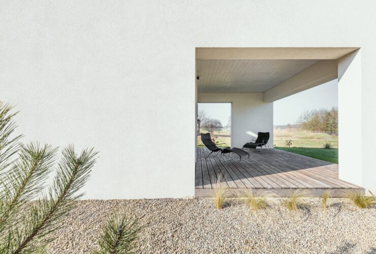 Black trendy armchairs on wooden patio of modern house