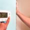 Homeowner adjusting thermostat on hvac using hands while wife watches and complains.