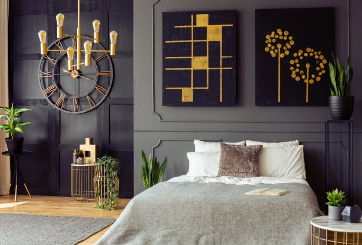 Plants and black and gold posters in grey bedroom interior with