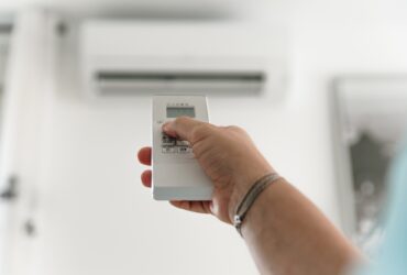 Woman's hand regulating the air conditioner with the remote control.