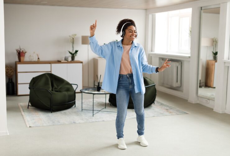 Black lady listening to music and dancing at home