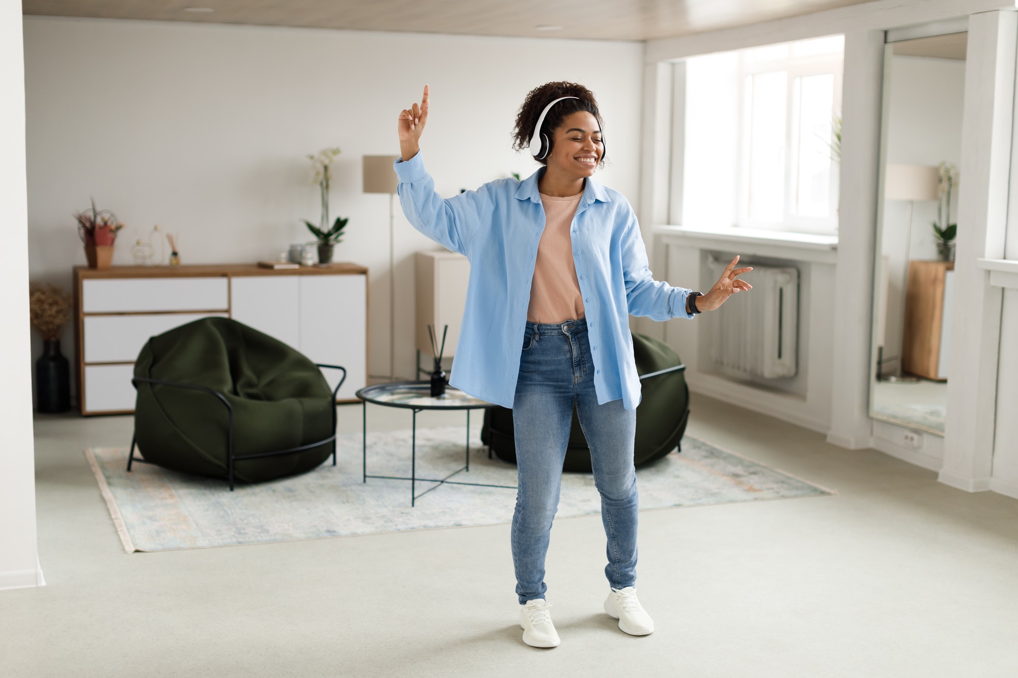 Black lady listening to music and dancing at home