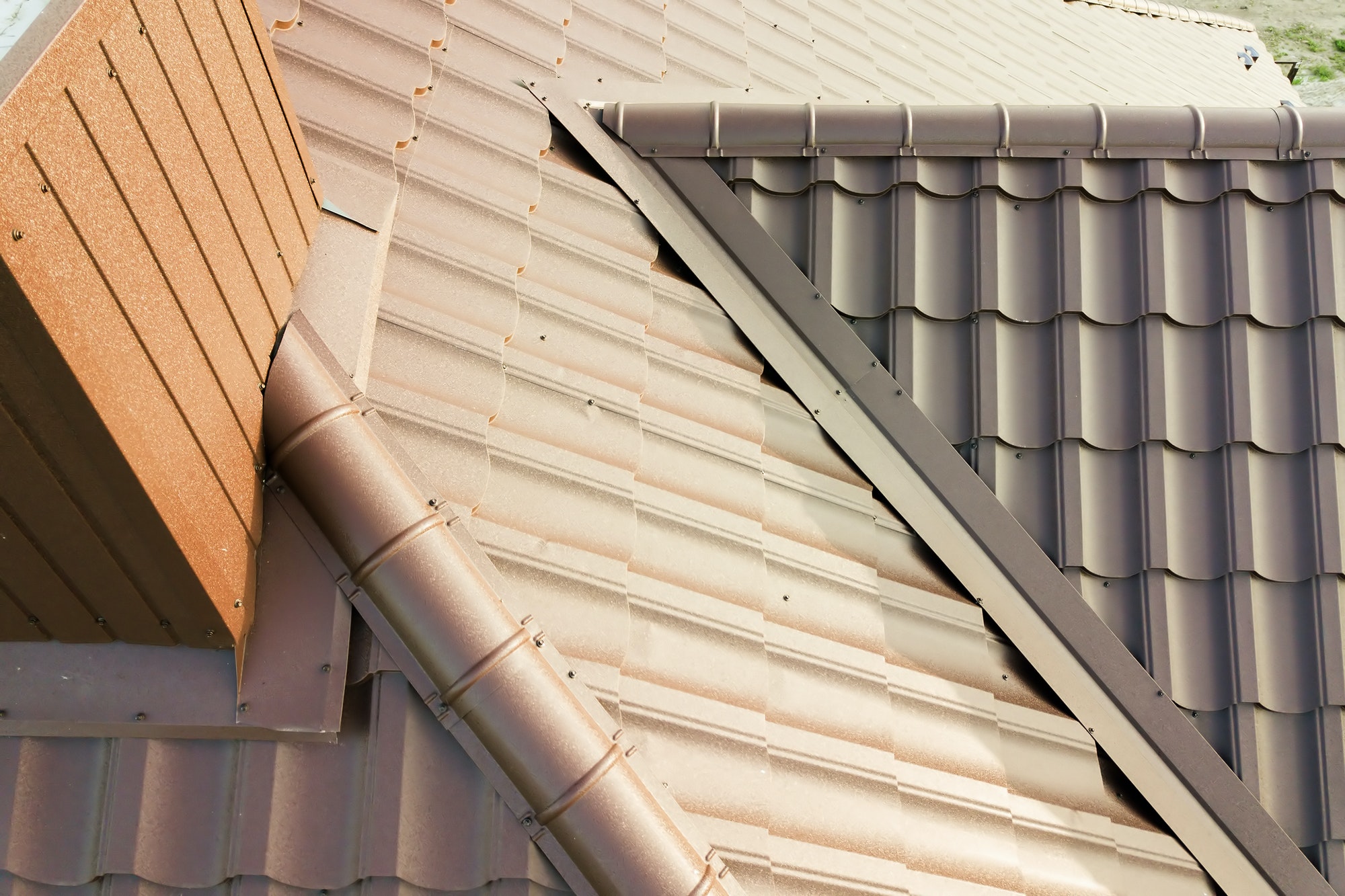 Detail of house roof structure covered with brown metal tile sheets