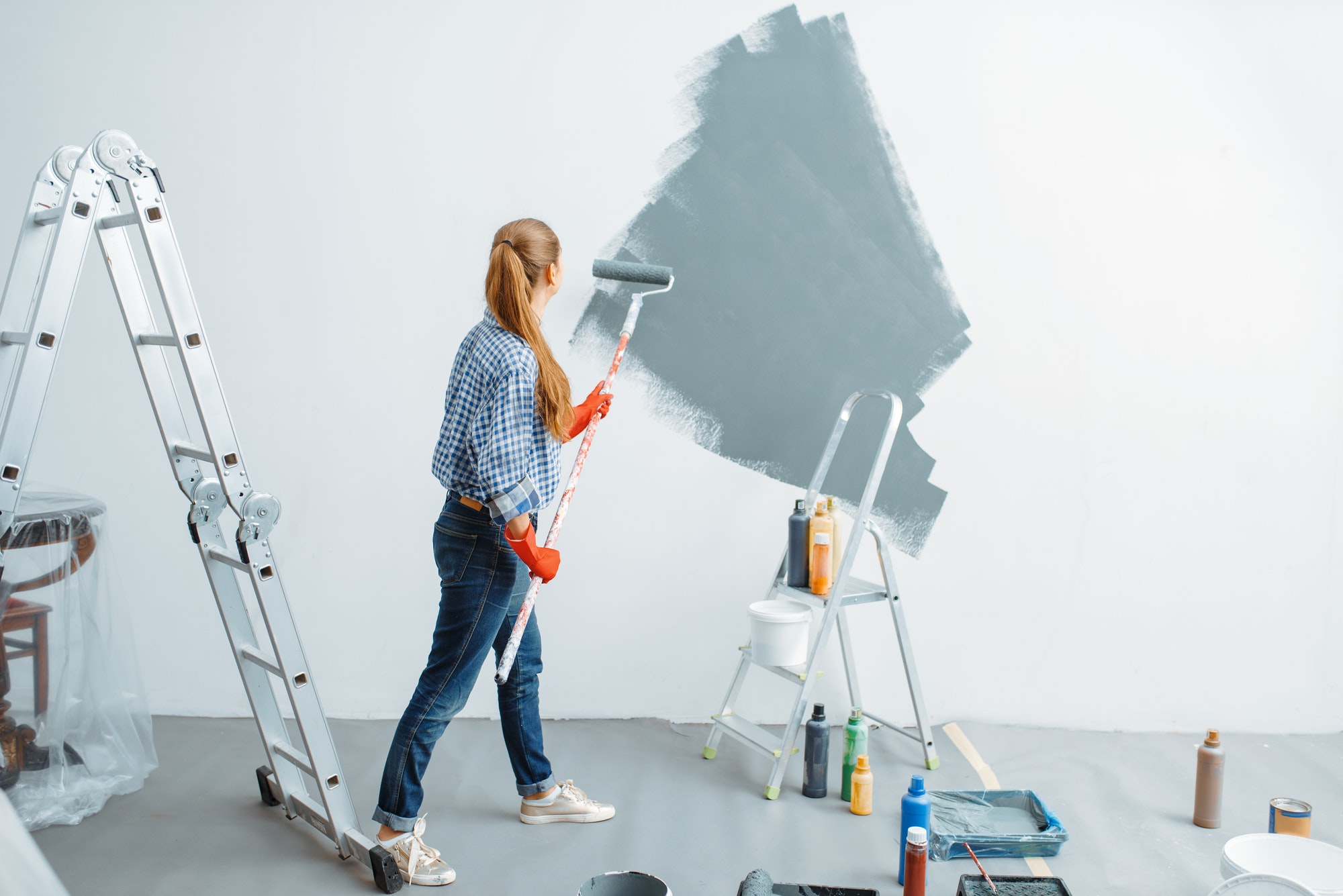 Female house painter paints wall