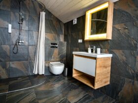 Interior of modern stylish bathroom with black tiled walls, curtain shower place and wooden