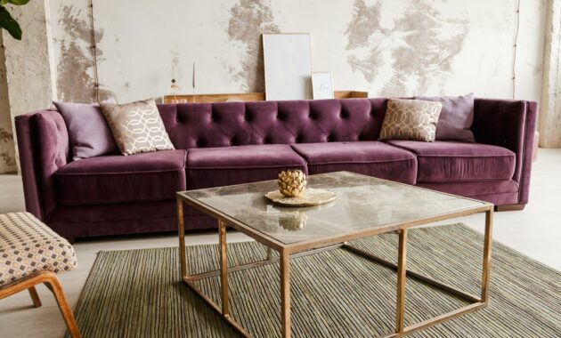 Purple velvet sofa with golden pillow in living room interior
