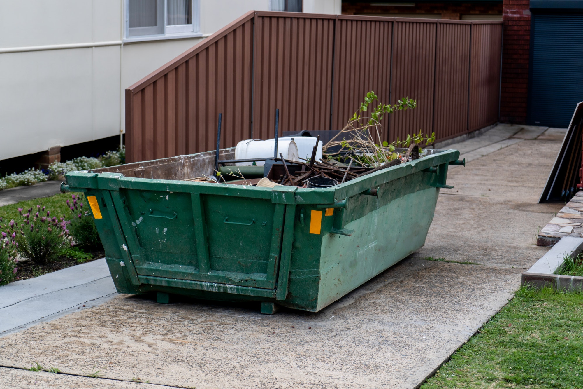Skip bin full of household waste rubbish. House clean up and renovation concept. Waste management