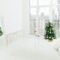 Spacious white bedroom with bed, decorated Christmas tree, mirror and dog on windowsill